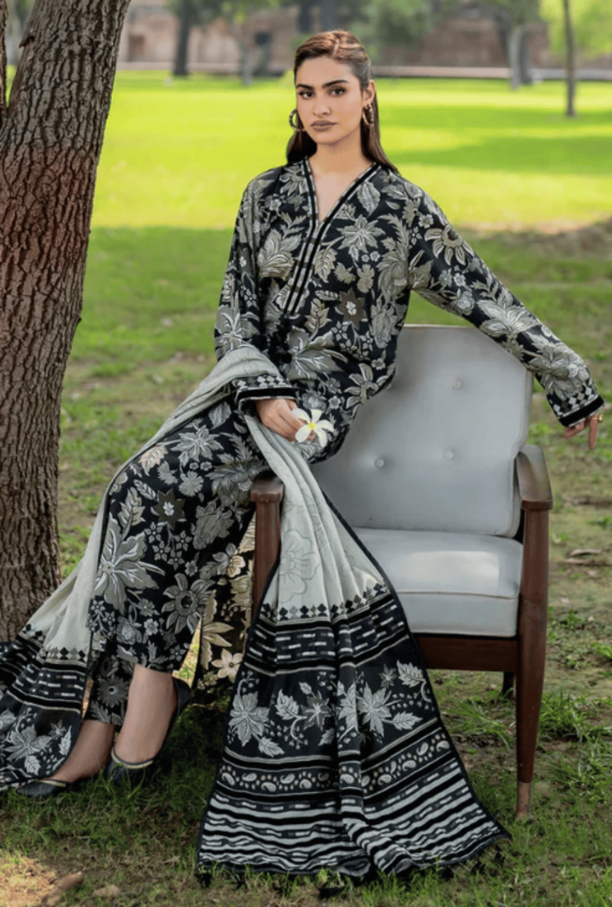 Woman in a black and white floral outfit sitting on a chair outdoors.