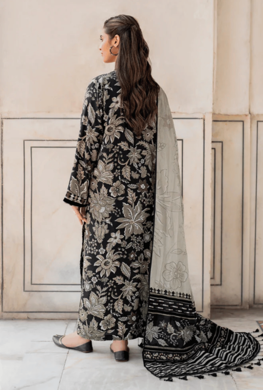 Woman wearing a black floral embroidered outfit with a white dupatta in an indoor setting.