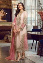 Woman in a traditional outfit with pink and gold embroidery in a modern living room.