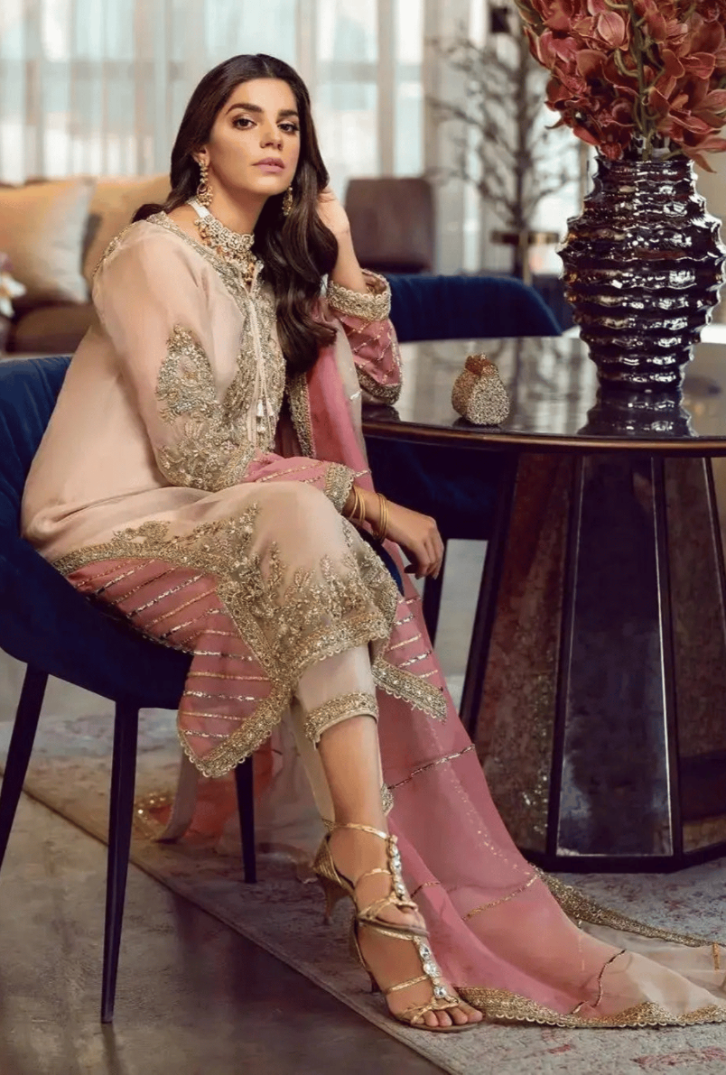 Woman in traditional outfit sitting in a stylish room with decor elements.