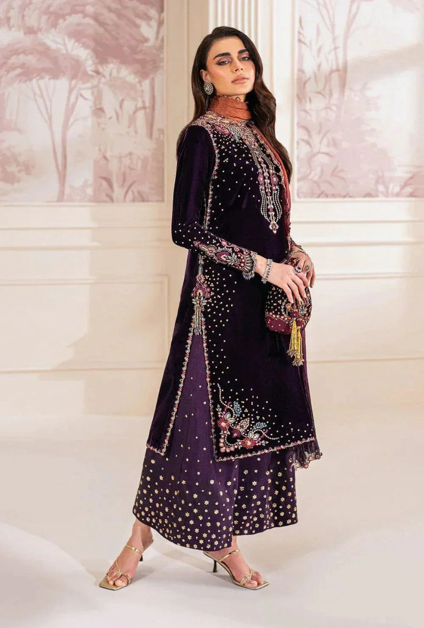 Woman wearing a dark purple embroidered traditional outfit in a decorated room.