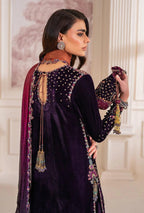 Woman wearing a dark purple embroidered outfit with a matching dupatta in an elegant indoor setting.