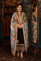 Woman in a floral embroidered outfit standing in front of a mirror with a decorative background.