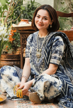 Woman in a blue and white floral dress sitting in a decorative indoor setting.